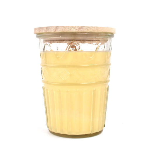 Glass jar of yellow liquid with a wooden lid.