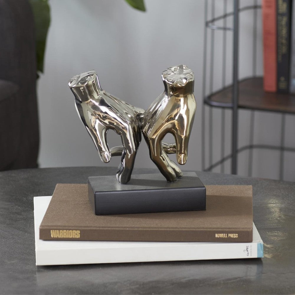 Silver sculpture on stacked books on a table.
