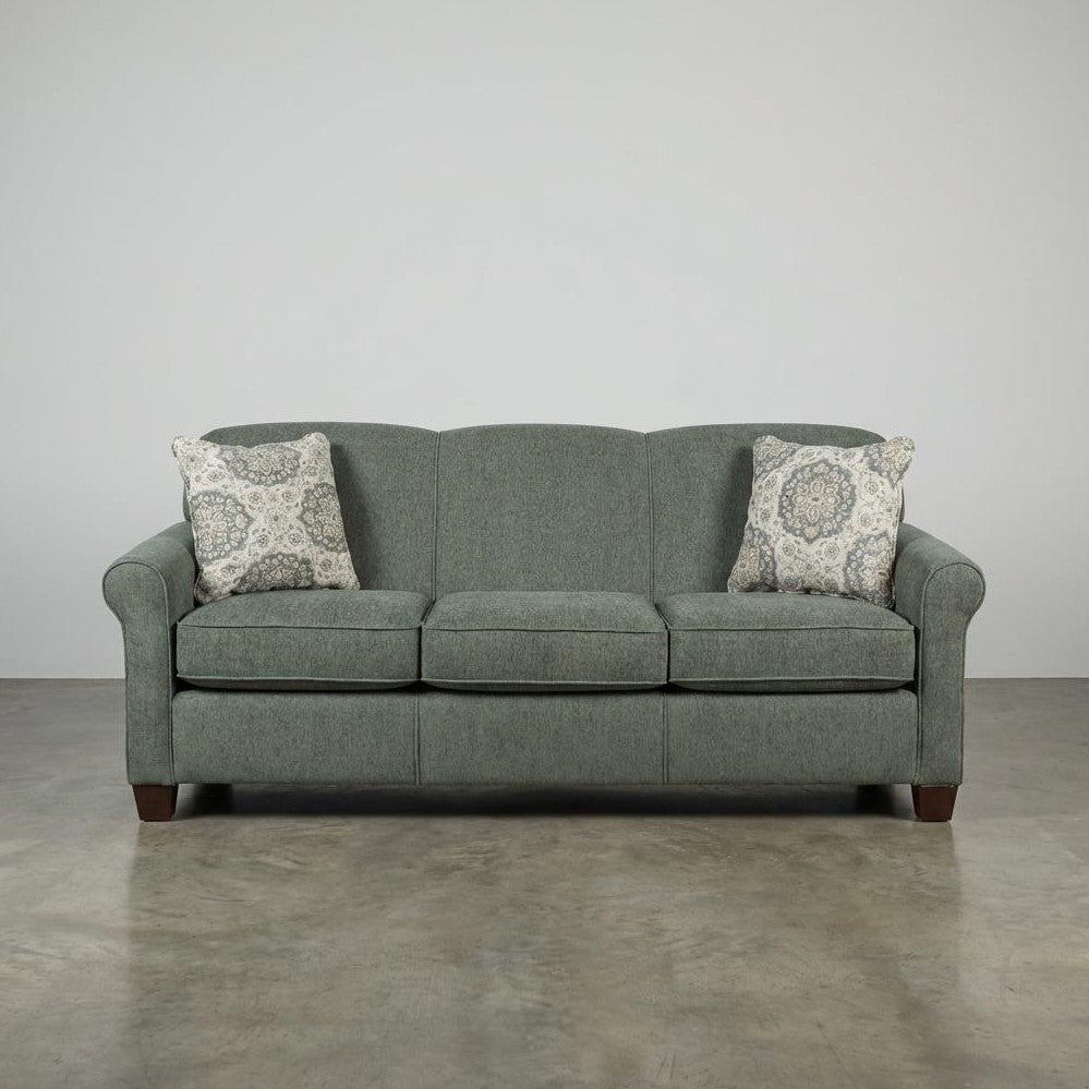 Gray sofa with two patterned pillows on a concrete floor.