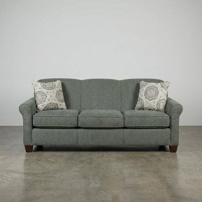 Gray sofa with two patterned pillows on a concrete floor.