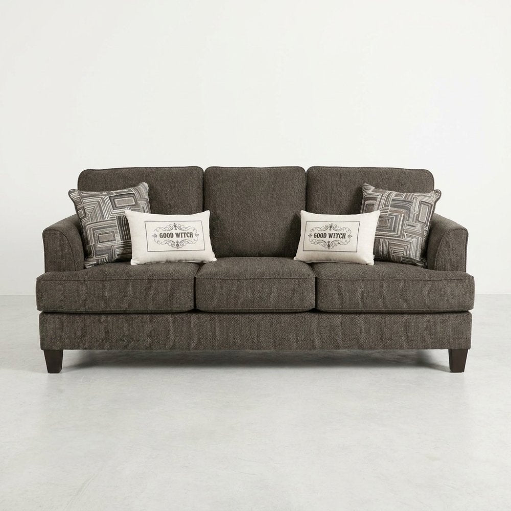 Brown sofa with patterned and "Good Witch" pillows.