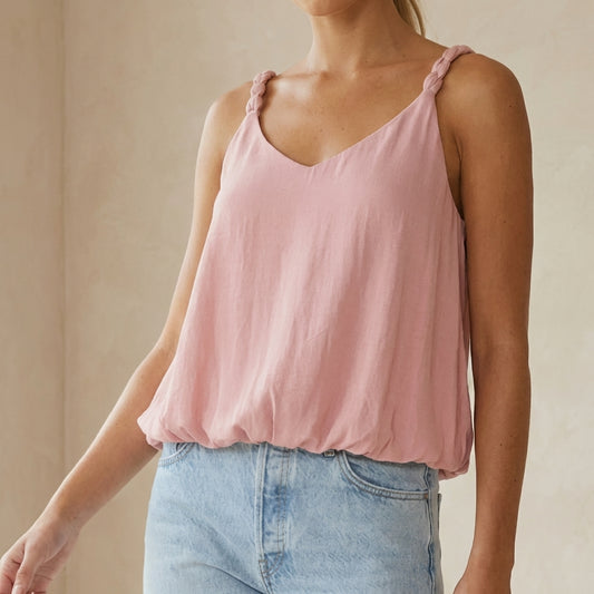 Woman wearing a pink sleeveless top and light blue jeans.