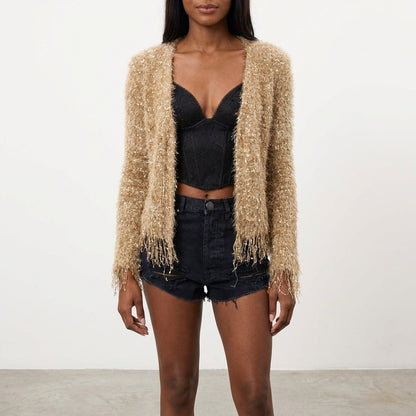 Woman in a fuzzy cardigan, black top, and denim shorts.