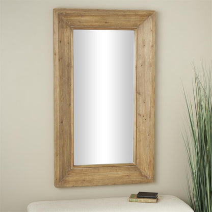 Wood-framed mirror on a beige wall, near books and a plant.