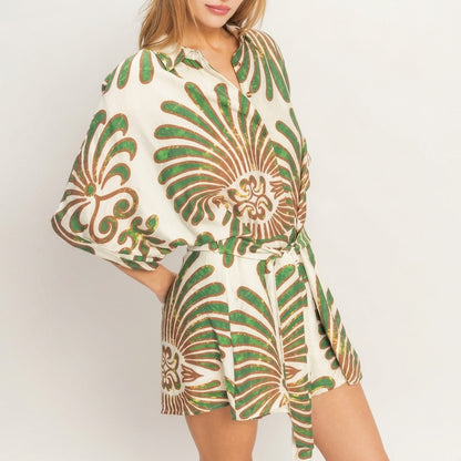 Woman in a patterned green and white romper, striking a pose.
