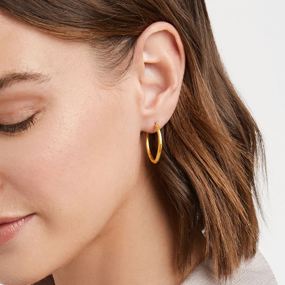Close-up of a woman wearing a simple gold hoop earring.