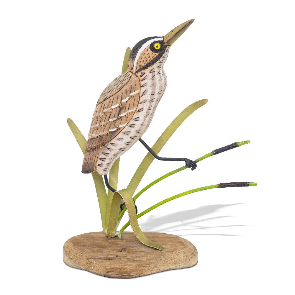 Wooden bird sculpture perched among reeds.