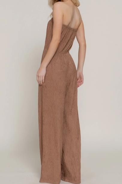 Person wearing a strapless, brown textured jumpsuit, facing away from the camera.