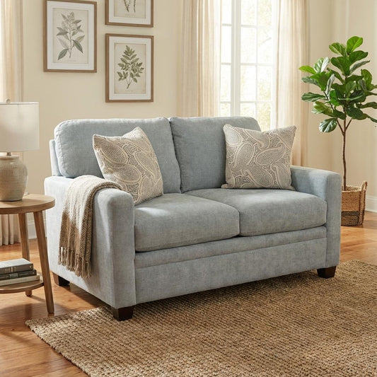 Cozy living room: light blue sofa, throw pillows, plant, and soft lighting.