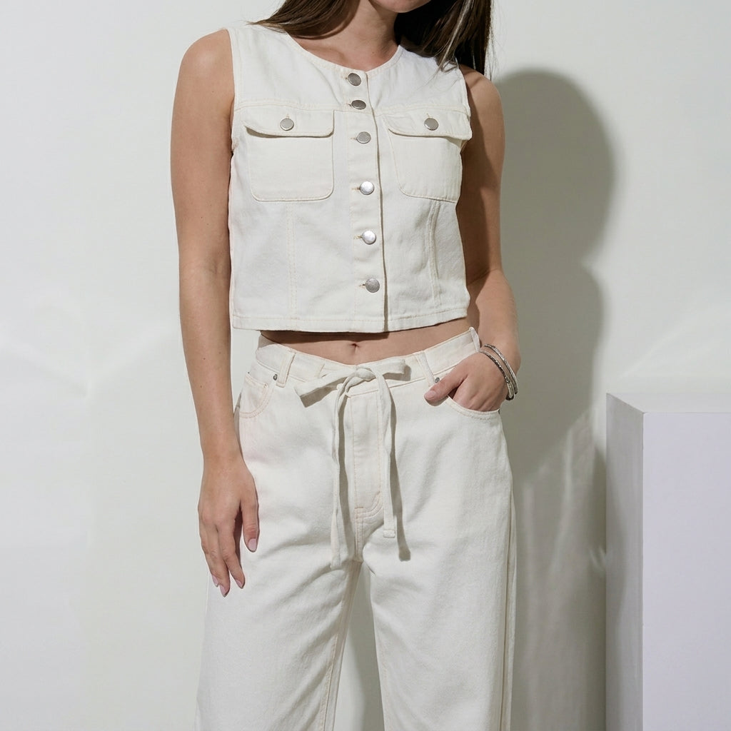 Woman in a white sleeveless top and pants, posing casually.