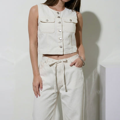Woman in a white sleeveless top and pants, posing casually.