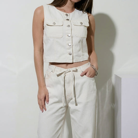 Woman in a white sleeveless top and pants, posing casually.