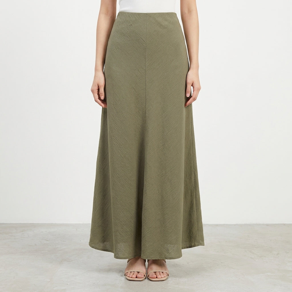 Model in a long, olive green A-line skirt and white top.