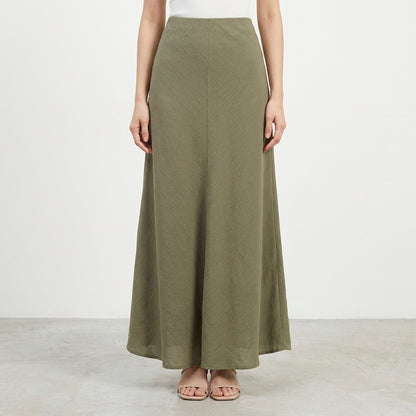 Model in a long, olive green A-line skirt and white top.