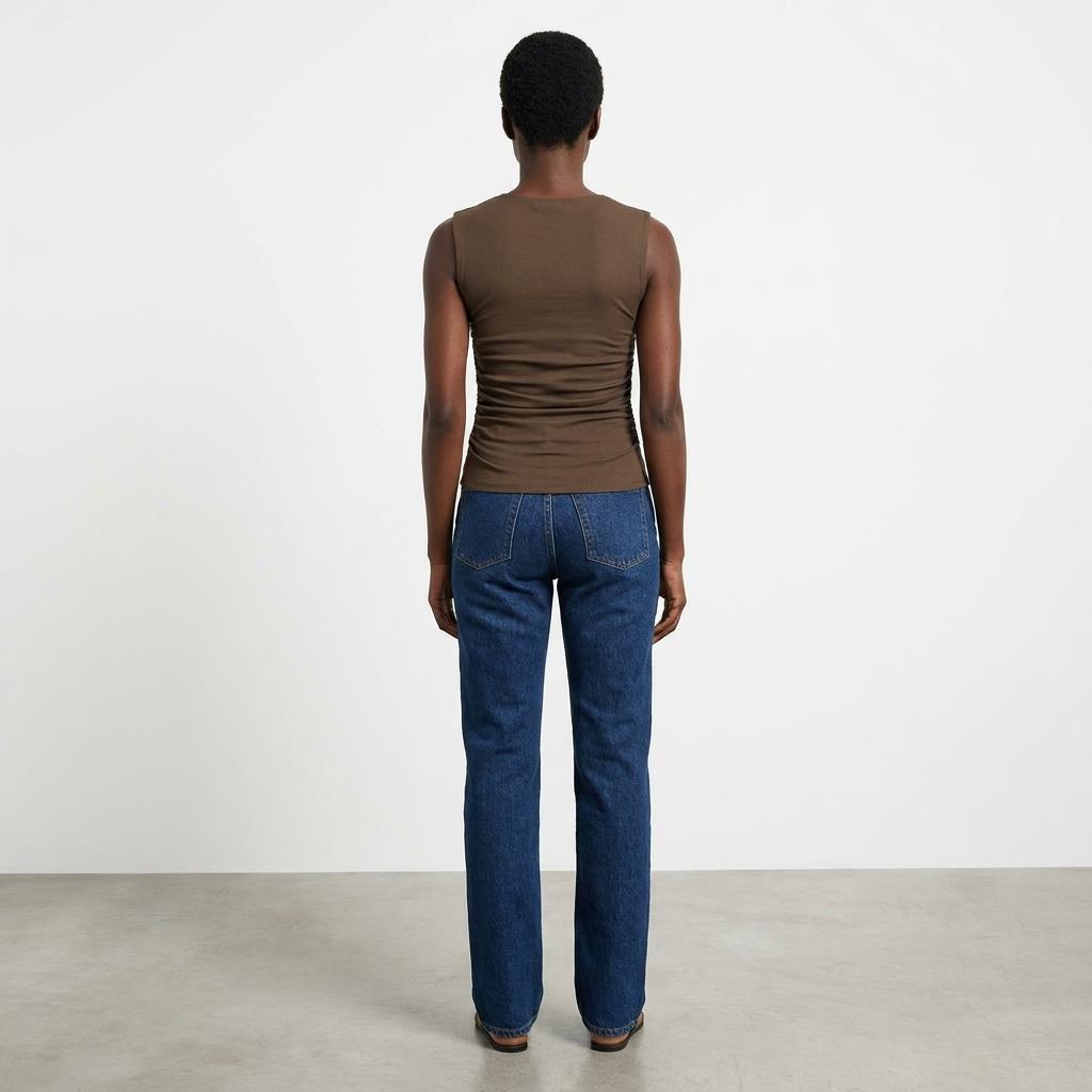 Person in brown tank and jeans, standing with back to the camera.