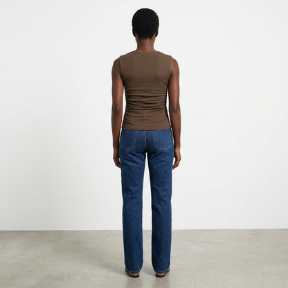 Person in brown tank and jeans, standing with back to the camera.