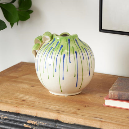 Colorful vase on a wooden table with books nearby.
