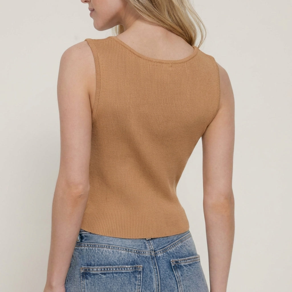 Woman in a tan sleeveless top and jeans, viewed from the side.