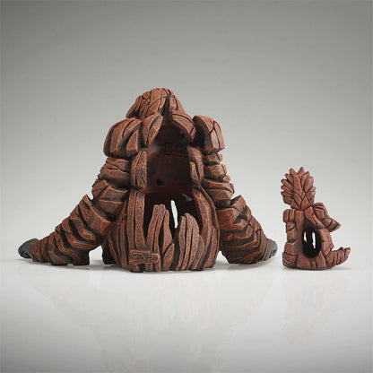 Wooden sculptures resembling abstract, organic forms on a reflective surface.