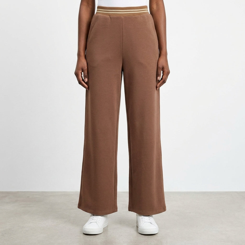Brown wide-leg pants with elastic waist, white sneakers, on clean floor.