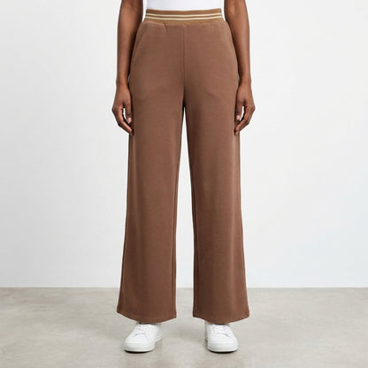 Brown wide-leg pants with elastic waist, white sneakers, on clean floor.