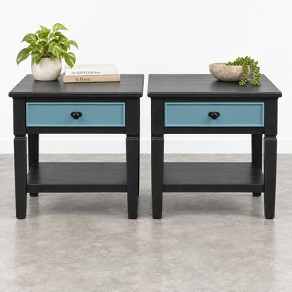 Two black end tables with blue drawers, plants, and books on each.