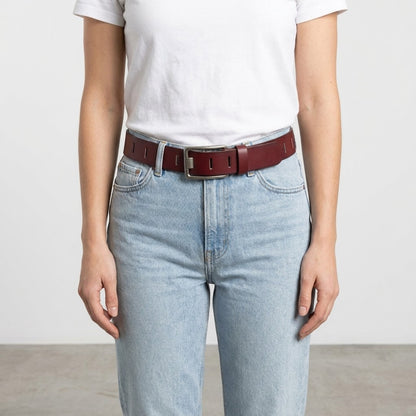 Person in white shirt, blue jeans, maroon belt.