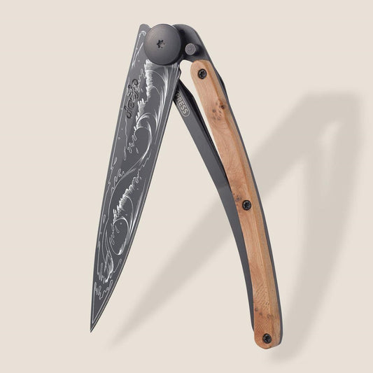 Ornate folding knife with wood handle, artistic blade engraving.