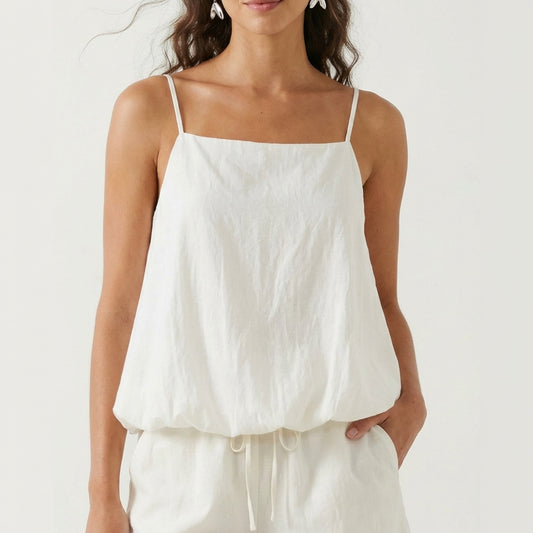 Woman in white spaghetti strap top with casual style.