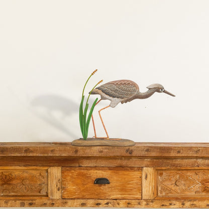 Wooden bird sculpture on a wooden cabinet with intricate carvings.