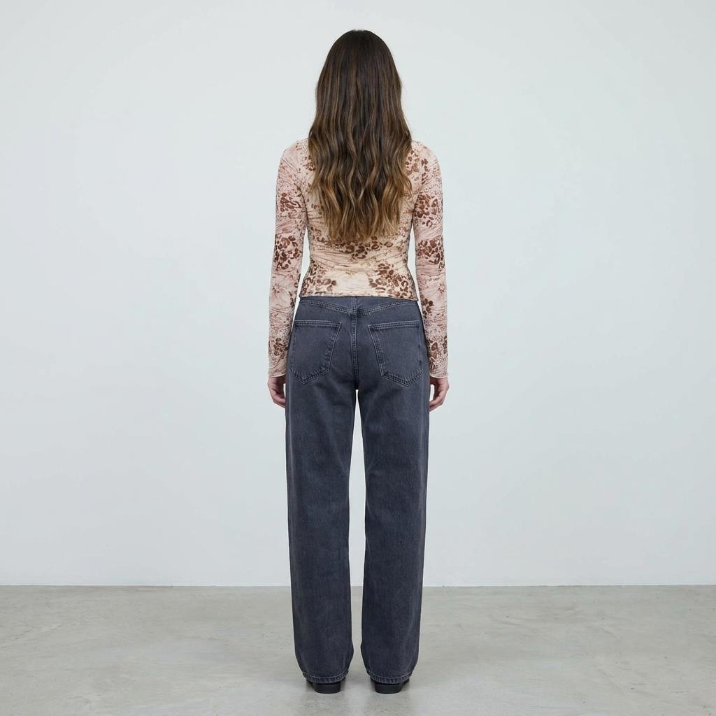 Person facing away in printed top and gray jeans.