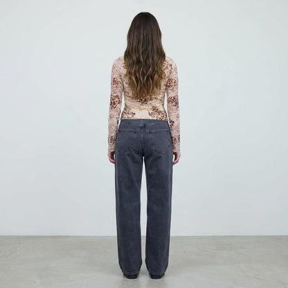 Person facing away in printed top and gray jeans.