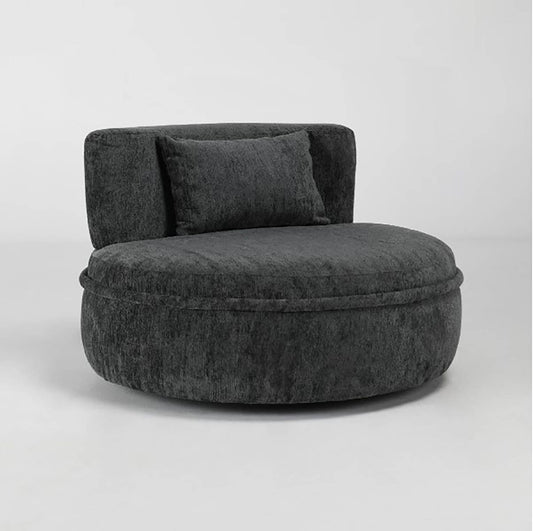 Dark gray, round plush chair with a matching pillow on a light background.