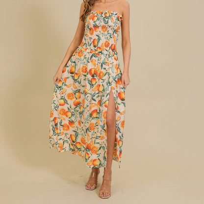 Woman in floral dress with orange patterns and slit, standing indoors.