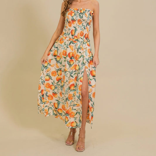 Woman in floral dress with orange patterns and slit, standing indoors.