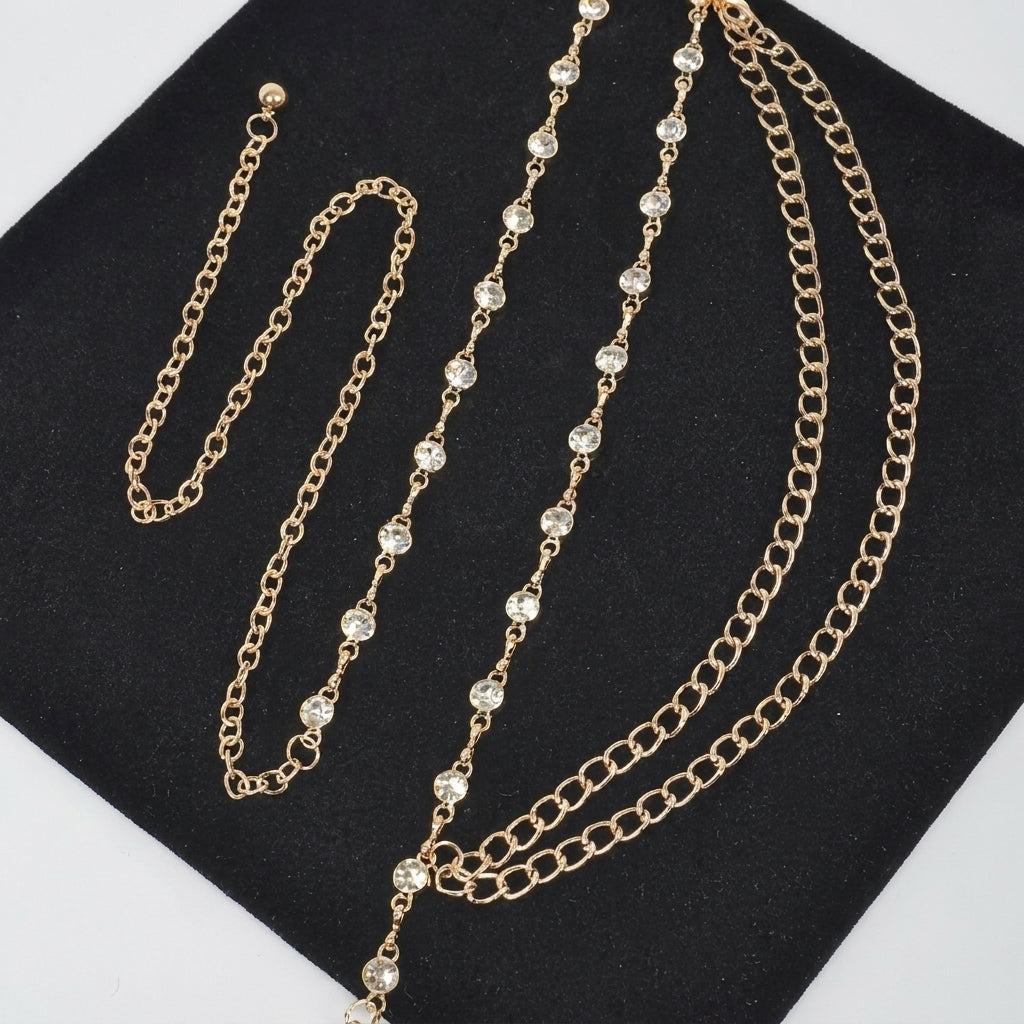 Gold chains with clear crystal accents laid on black fabric.