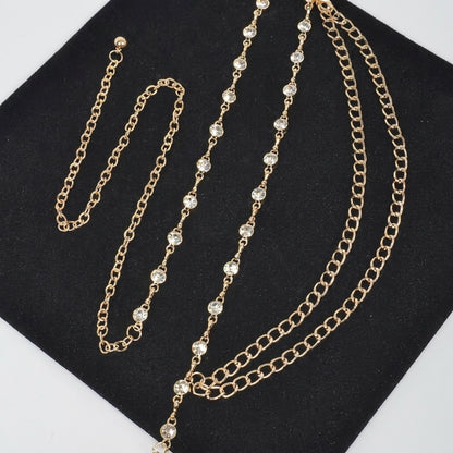 Gold chains with clear crystal accents laid on black fabric.