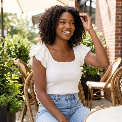 Smiling woman in white top sitting outside at a café.