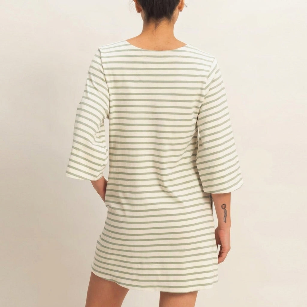 Person in a striped dress with tattoo on arm, facing away.