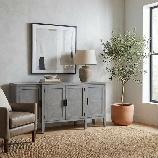 A gray wooden sideboard with four panel doors and black handles.