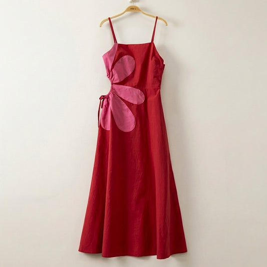 Red dress with pink floral side detail on a wooden hanger.
