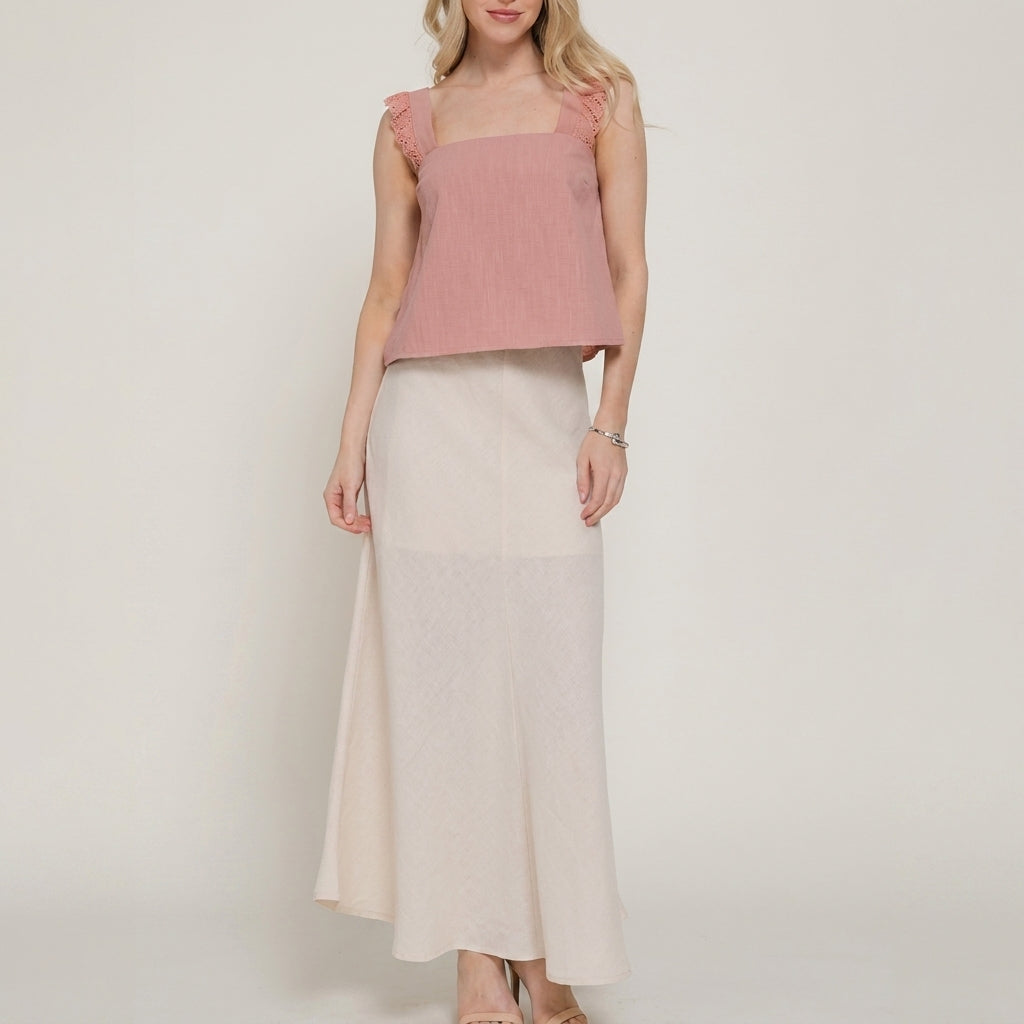 Woman in pink top and long cream skirt.