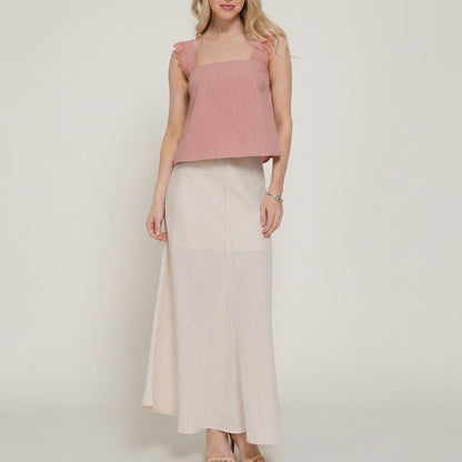 Woman in pink top and long cream skirt.