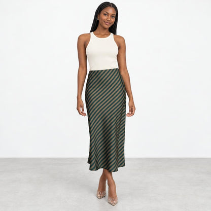 A woman models a white tank top and striped midi skirt in a bright studio.
