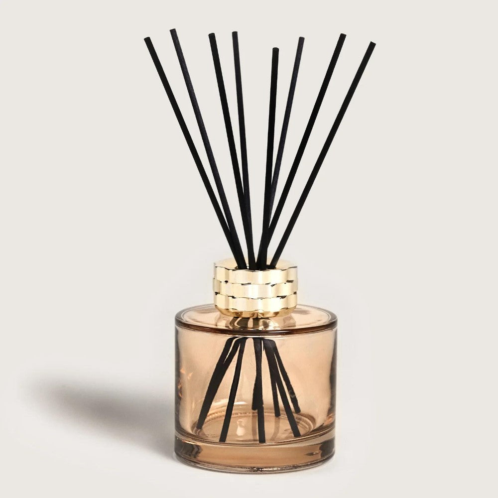 Glass diffuser jar with black reeds and gold accent.