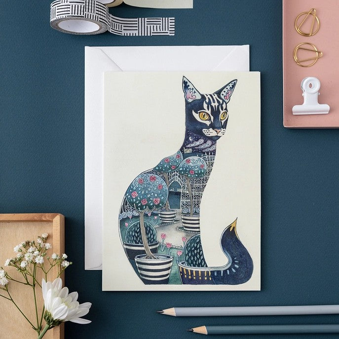 Artistic cat card with garden design, on a blue table with stationary items.