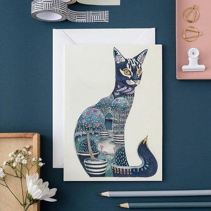 Artistic cat card with garden design, on a blue table with stationary items.