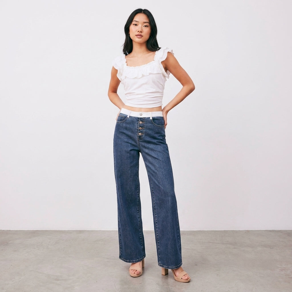Woman in white top and jeans posing against a plain background.