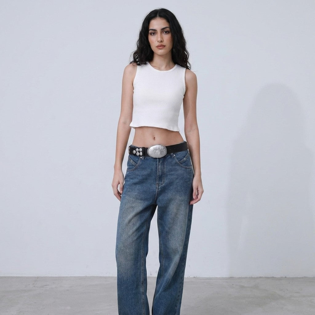 Person in white crop top and jeans, standing against a plain background.