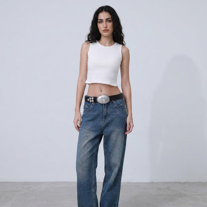 Person in white crop top and jeans, standing against a plain background.